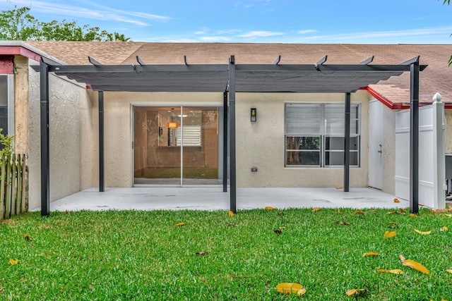 rear view of house featuring a pergola, stucco siding, a patio, and a lawn
