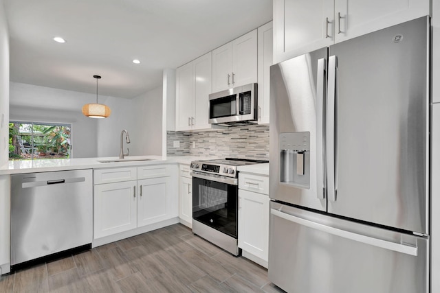kitchen with appliances with stainless steel finishes, a sink, light countertops, white cabinets, and recessed lighting