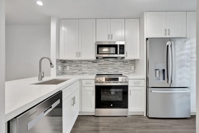 kitchen featuring stainless steel appliances, a sink, white cabinets, recessed lighting, and decorative backsplash