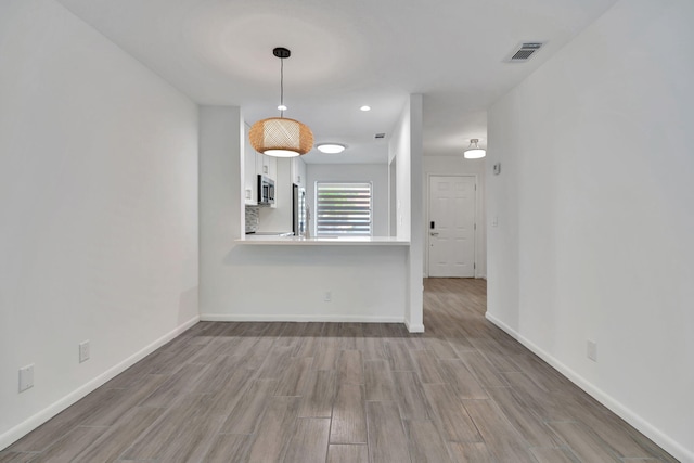 unfurnished dining area with wood finished floors, baseboards, and recessed lighting
