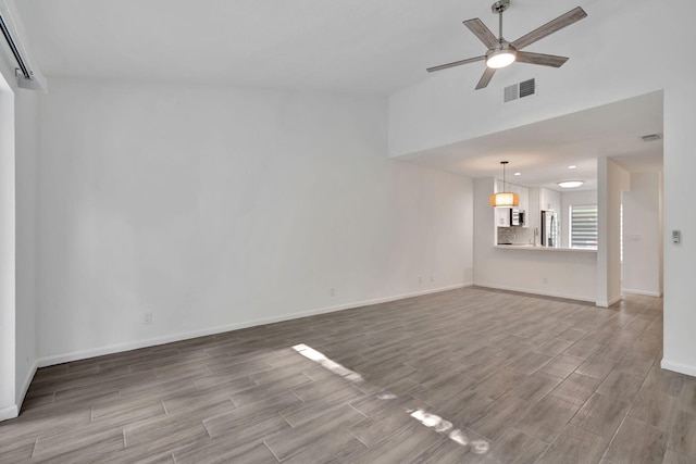 unfurnished living room with wood finished floors, a ceiling fan, baseboards, and lofted ceiling