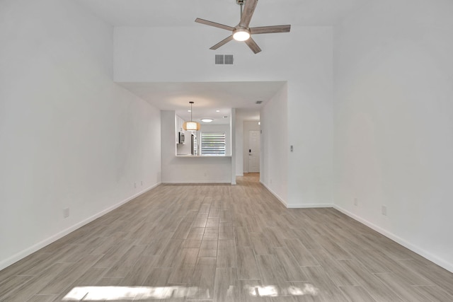 unfurnished room featuring light wood-type flooring, a ceiling fan, and baseboards
