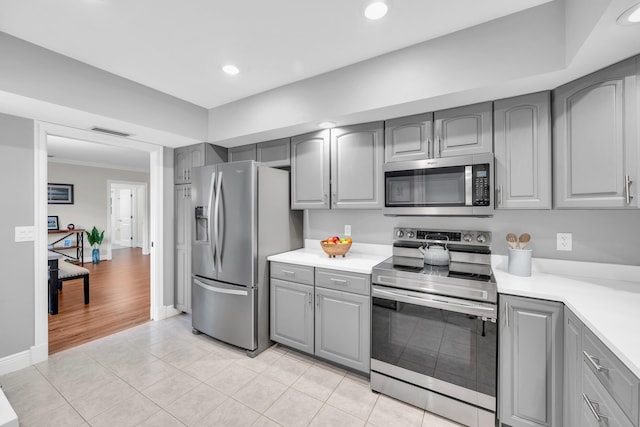 kitchen with gray cabinets, stainless steel appliances, light countertops, light tile patterned flooring, and recessed lighting