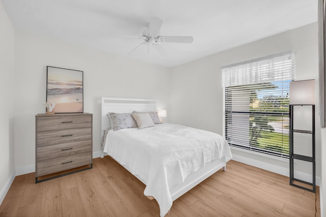 bedroom featuring baseboards, light wood-style floors, and ceiling fan