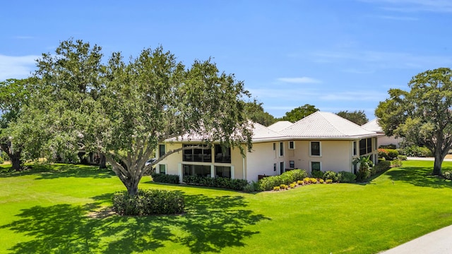 view of home's exterior featuring a lawn, a tile roof, and stucco siding