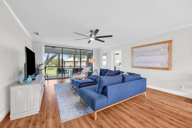 living room featuring crown molding, light wood-style floors, baseboards, and a ceiling fan