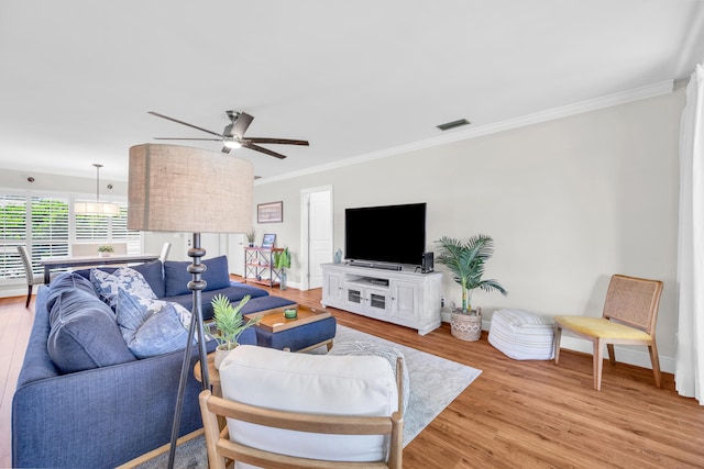 living room featuring crown molding, light wood-type flooring, ceiling fan, and baseboards