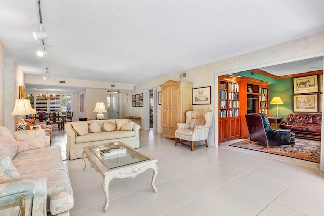 living room featuring track lighting, tile patterned floors, a textured ceiling, and a chandelier