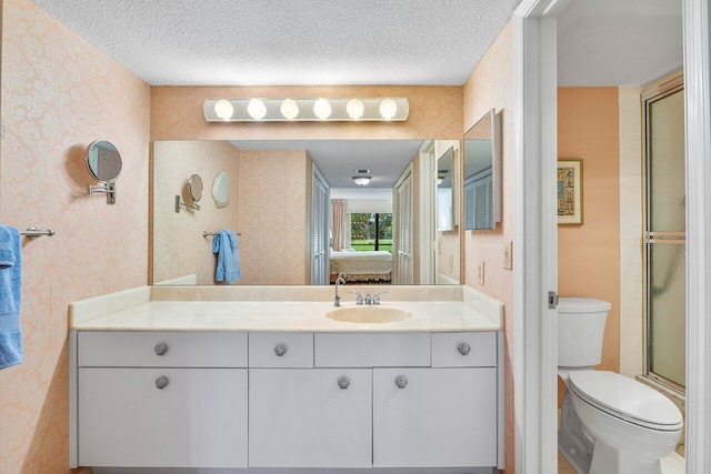 full bathroom with wallpapered walls, toilet, a textured ceiling, a shower with shower door, and vanity