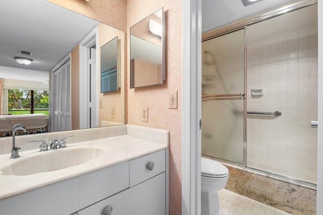 full bath with a stall shower, a textured ceiling, vanity, toilet, and tile patterned floors