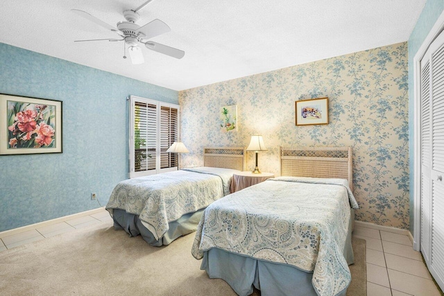 tiled bedroom with a closet, wallpapered walls, baseboards, ceiling fan, and a textured ceiling