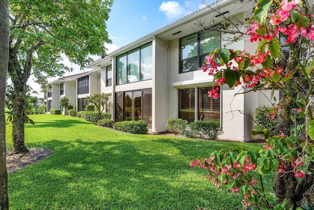 rear view of property featuring stucco siding and a yard