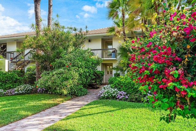 view of front of home featuring stucco siding, a front lawn, and a tiled roof