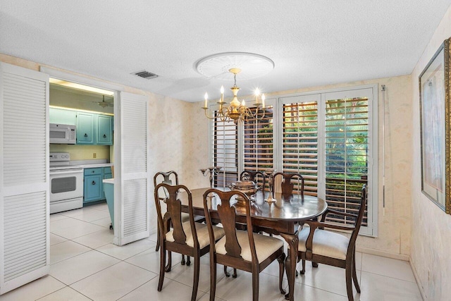 dining area with a chandelier, a textured ceiling, and light tile patterned flooring