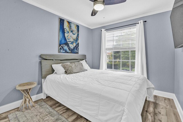 bedroom featuring crown molding, baseboards, wood finished floors, and a ceiling fan