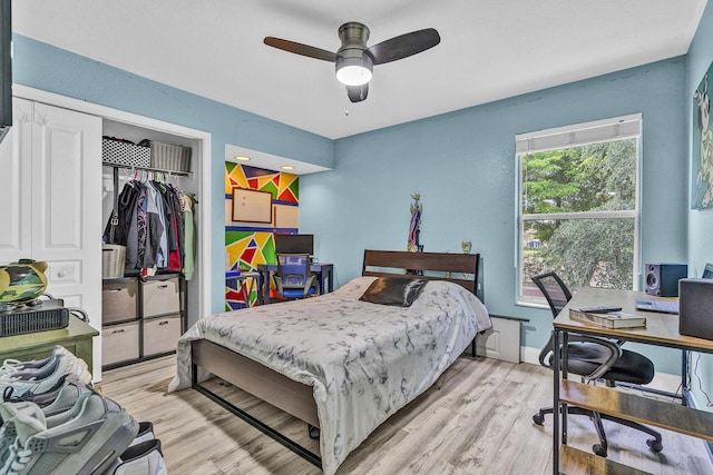bedroom featuring an office area, a closet, light wood finished floors, baseboards, and a ceiling fan