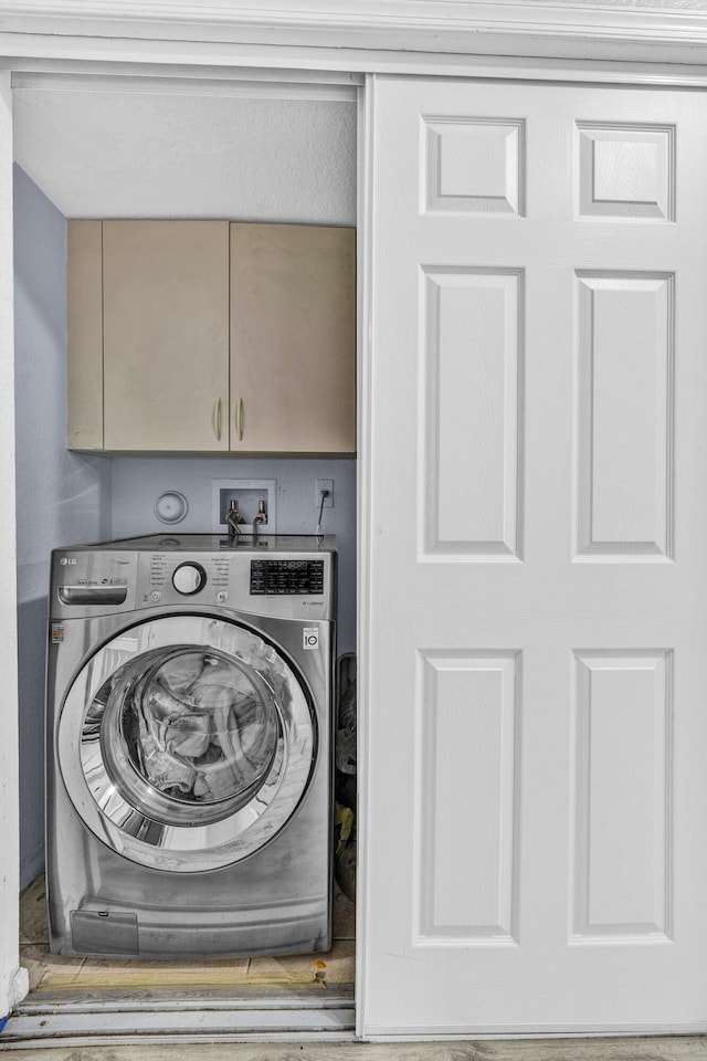 clothes washing area with washer / dryer and cabinet space