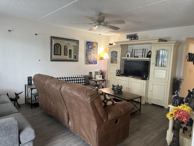 living area with a textured ceiling, dark wood-type flooring, baseboards, and a ceiling fan