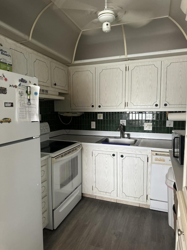 kitchen featuring a sink, white appliances, dark wood finished floors, under cabinet range hood, and backsplash