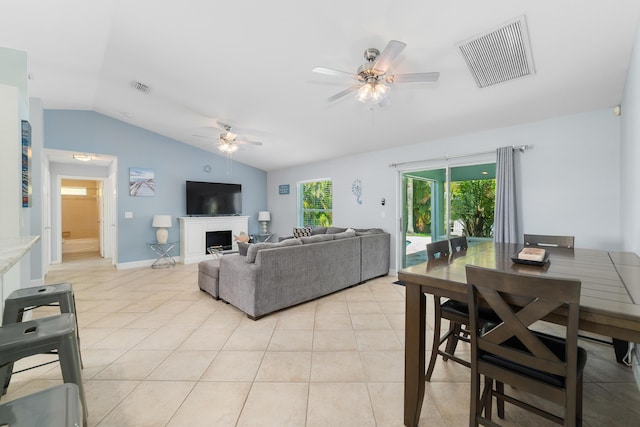 living area with a ceiling fan, lofted ceiling, light tile patterned floors, and a fireplace