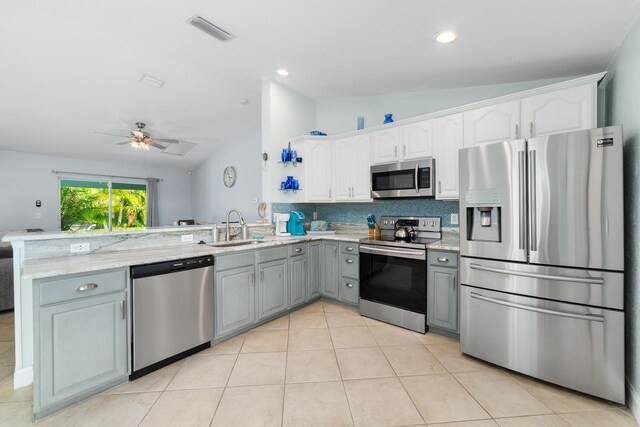 kitchen featuring stainless steel appliances, gray cabinetry, lofted ceiling, a peninsula, and a sink
