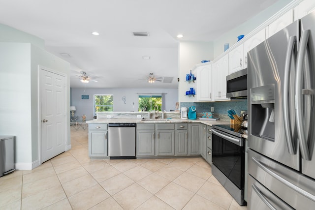 kitchen with stainless steel appliances, a sink, a peninsula, a ceiling fan, and gray cabinets