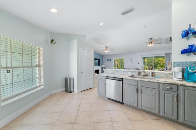 kitchen featuring dishwasher, a sink, gray cabinetry, a fireplace, and a ceiling fan