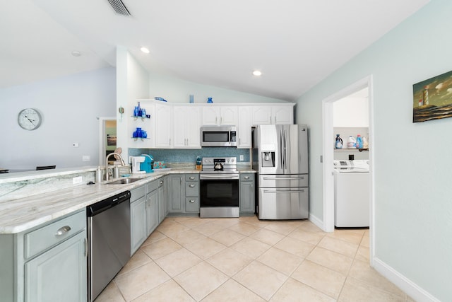 kitchen with appliances with stainless steel finishes, a sink, lofted ceiling, white cabinets, and light tile patterned floors