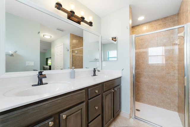 full bath featuring a stall shower, double vanity, and tile patterned floors