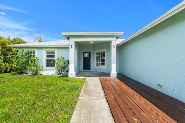 doorway to property featuring stucco siding and a yard