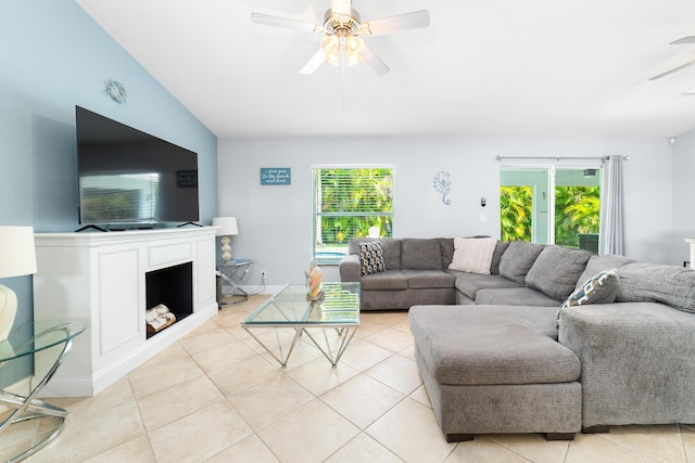 living area featuring a ceiling fan, healthy amount of natural light, light tile patterned floors, and lofted ceiling