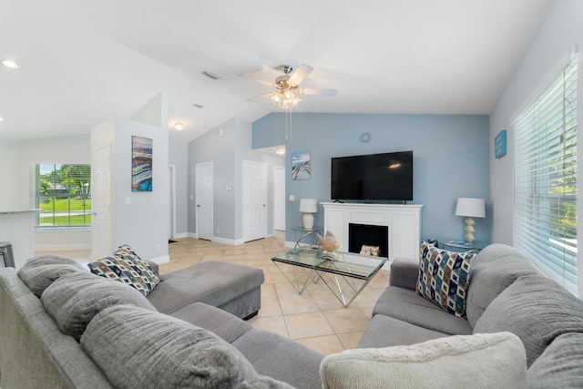 living room with light tile patterned floors, a ceiling fan, vaulted ceiling, baseboards, and a fireplace