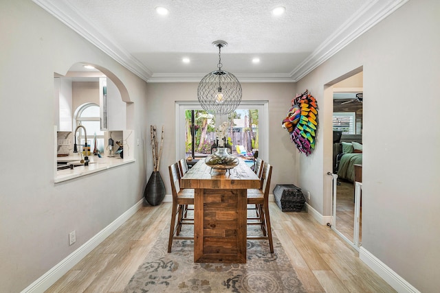 1707 NW 38th St, Oakland Park, FL 33309 - dining area featuring crown molding, light wood-type flooring, a textured ceiling, arched walkways, and recessed lighting