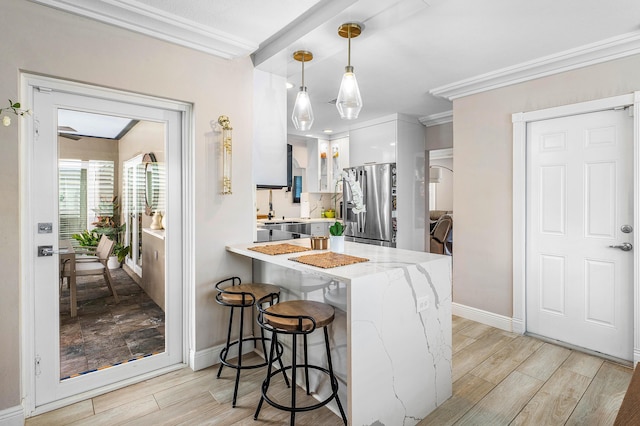 1707 NW 38th St, Oakland Park, FL 33309 - kitchen with stainless steel fridge, a peninsula, white cabinets, light wood-style flooring, and crown molding
