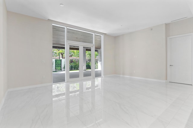 spare room featuring light marble finish floors, baseboards, and french doors