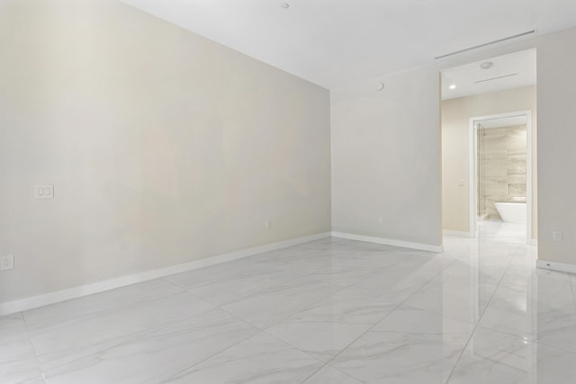 unfurnished room featuring light marble finish flooring and baseboards