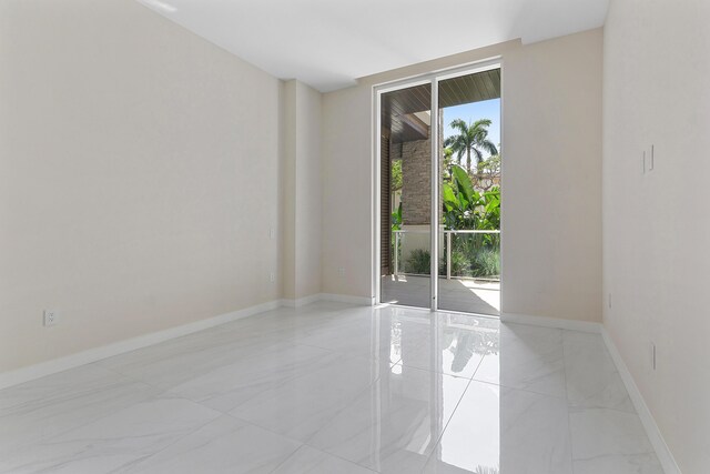 empty room featuring light marble finish flooring and baseboards