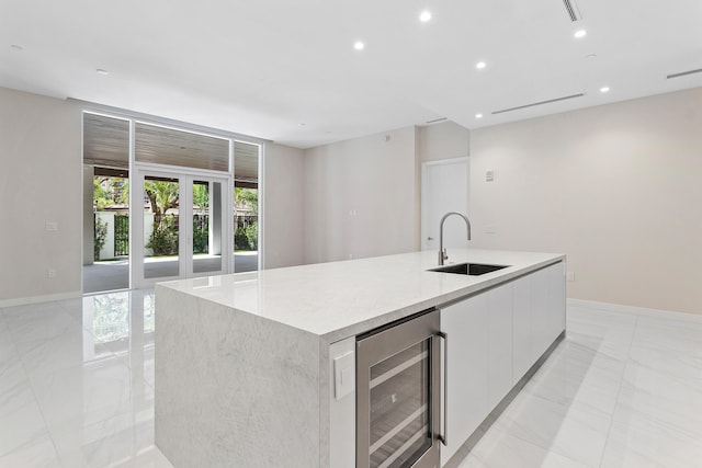kitchen featuring beverage cooler, a sink, modern cabinets, light marble finish floors, and recessed lighting