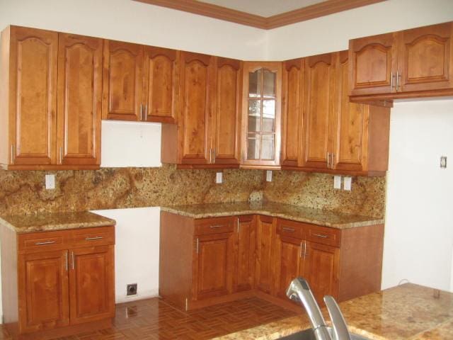 kitchen featuring brown cabinets, light stone counters, and decorative backsplash