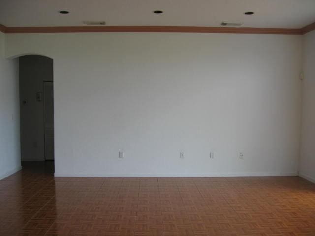 spare room with ornamental molding, arched walkways, and visible vents