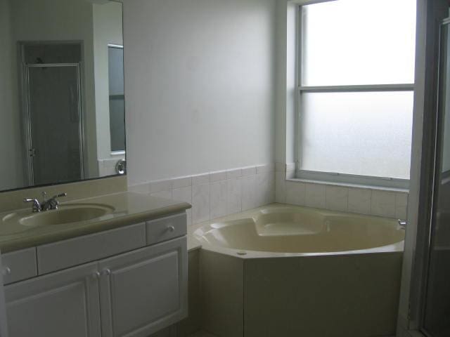full bathroom with a bath, vanity, and a shower stall