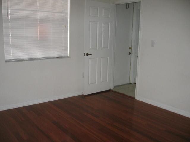 spare room featuring baseboards and wood finished floors