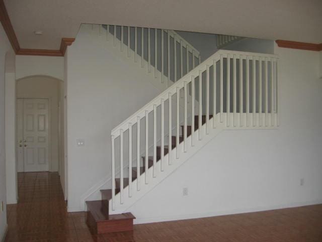 stairway featuring ornamental molding and arched walkways