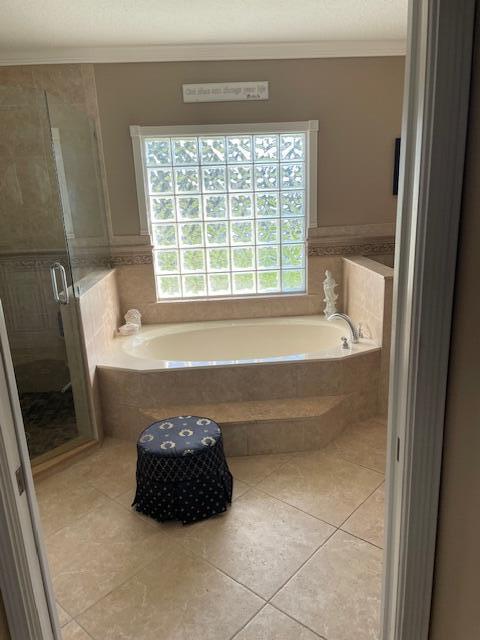 1618 SW Lexington Dr NW, Port Saint Lucie, FL 34953 - full bathroom with tile patterned floors, crown molding, a garden tub, a shower stall, and a wainscoted wall