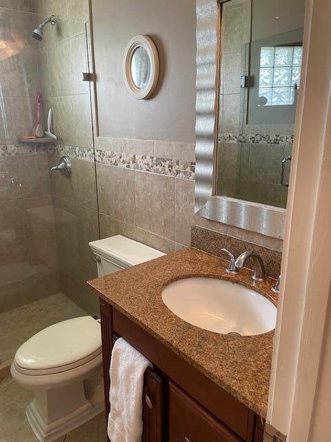 1618 SW Lexington Dr NW, Port Saint Lucie, FL 34953 - bathroom featuring toilet, tiled shower, tile walls, and vanity