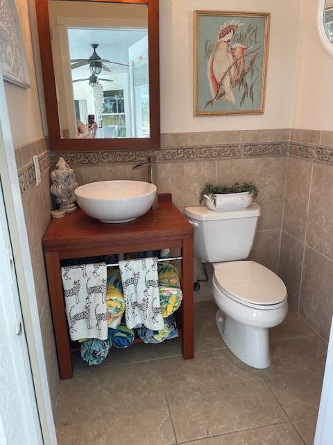 1618 SW Lexington Dr NW, Port Saint Lucie, FL 34953 - half bath with tile walls, a wainscoted wall, toilet, tile patterned floors, and a ceiling fan