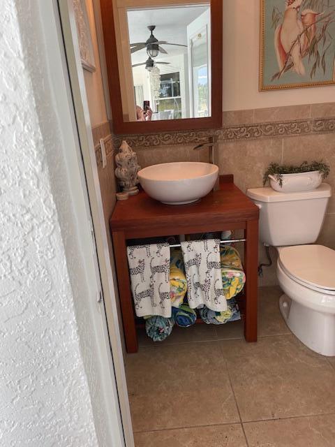 1618 SW Lexington Dr NW, Port Saint Lucie, FL 34953 - bathroom with tile walls, tile patterned floors, toilet, a wainscoted wall, and a ceiling fan