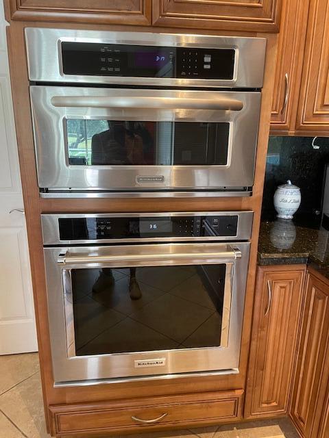 1618 SW Lexington Dr NW, Port Saint Lucie, FL 34953 - kitchen view of brown cabinetry, stainless steel double oven, and dark stone counters