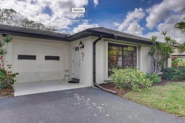 4728 Finchwood Rd Unit B, Boynton Beach, FL 33436 - view of exterior entry with asphalt driveway, a garage, and stucco siding