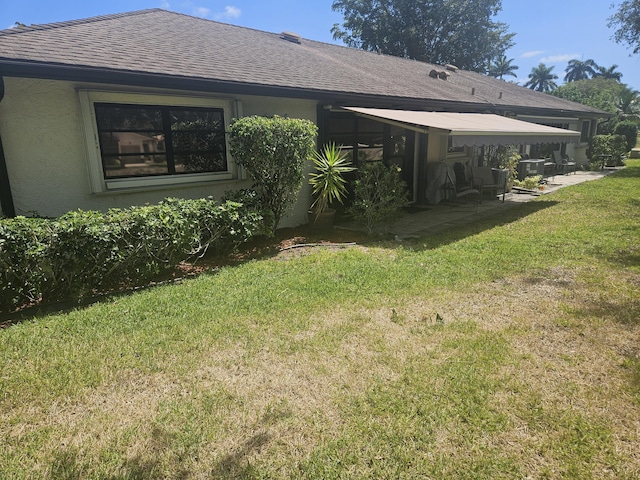 4728 Finchwood Rd Unit B, Boynton Beach, FL 33436 - rear view of property featuring a lawn, stucco siding, a shingled roof, a patio area, and central AC